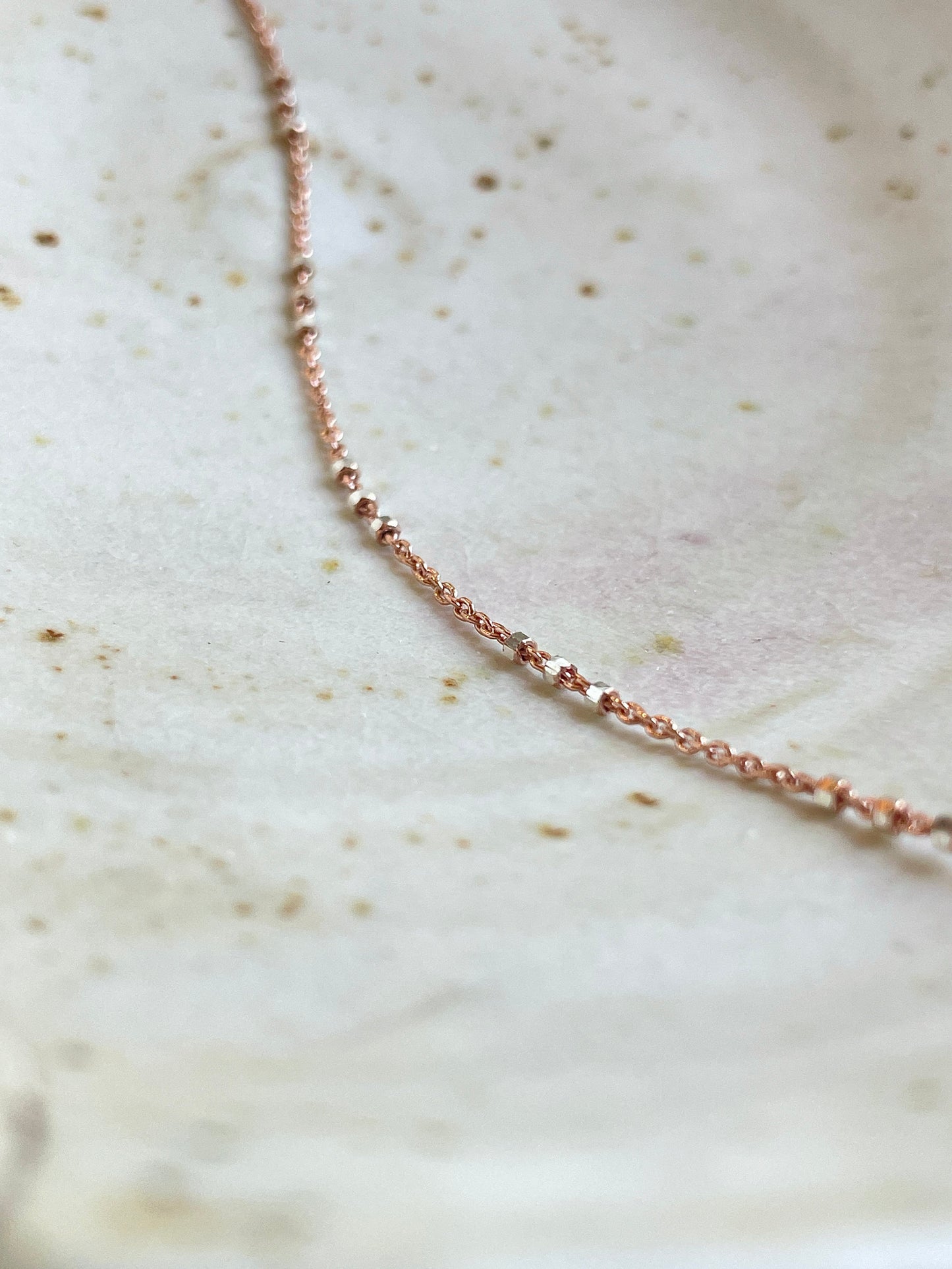 Two-tone Rose Gold and Sterling Silver satellite chain necklace featuring small silver beads spaced in sets of threes for a chic and contemporary look. This shows the details.