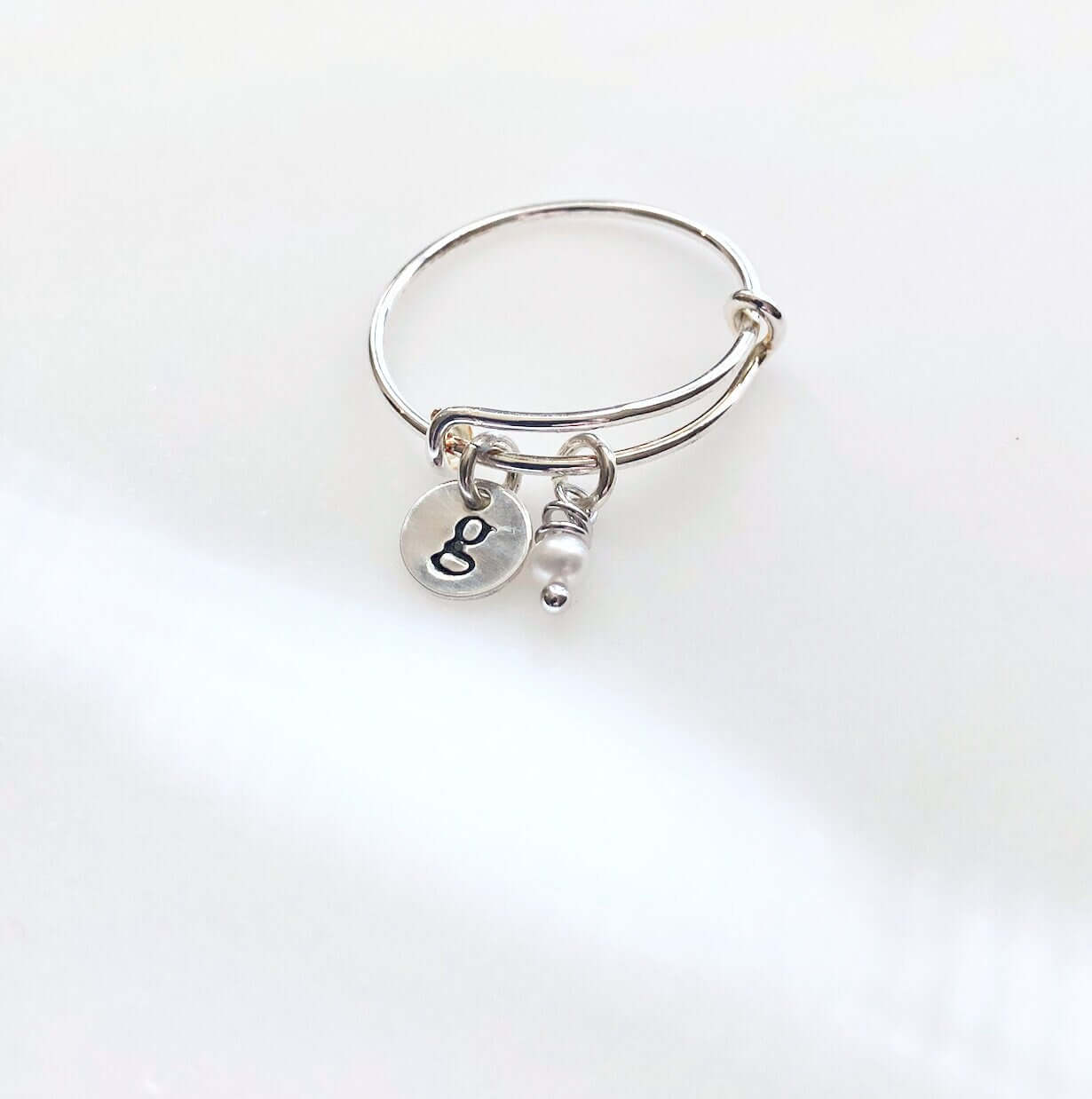 Adjustable Personalized Silver Charm Ring with stamped disc g and pearl on grey background