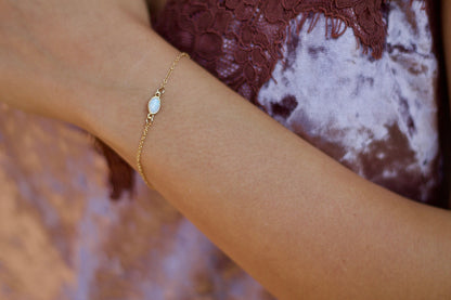 Dainty opal bracelet featuring genuine white fire opal stone on a 14K gold-filled chain, perfect for everyday wear and water-friendly.