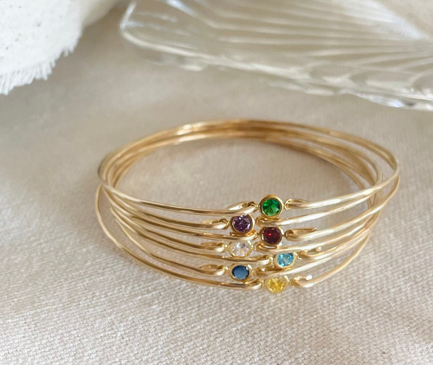 Dainty birthstone bangle featuring sparkling CZ diamonds, ideal for stacking and layering, perfect for brides, bridesmaids, and gifts. Bangles on Fabric.